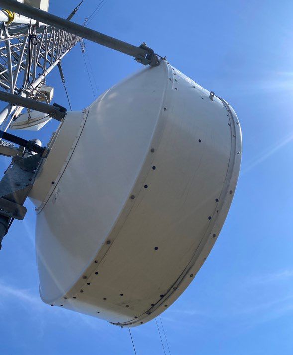 A satellite dish on top of a tower with a blue sky in the background