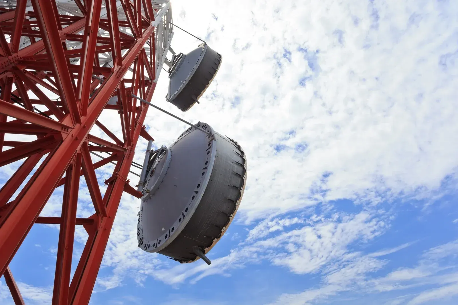 A red tower with antennas hanging from it against a blue sky.