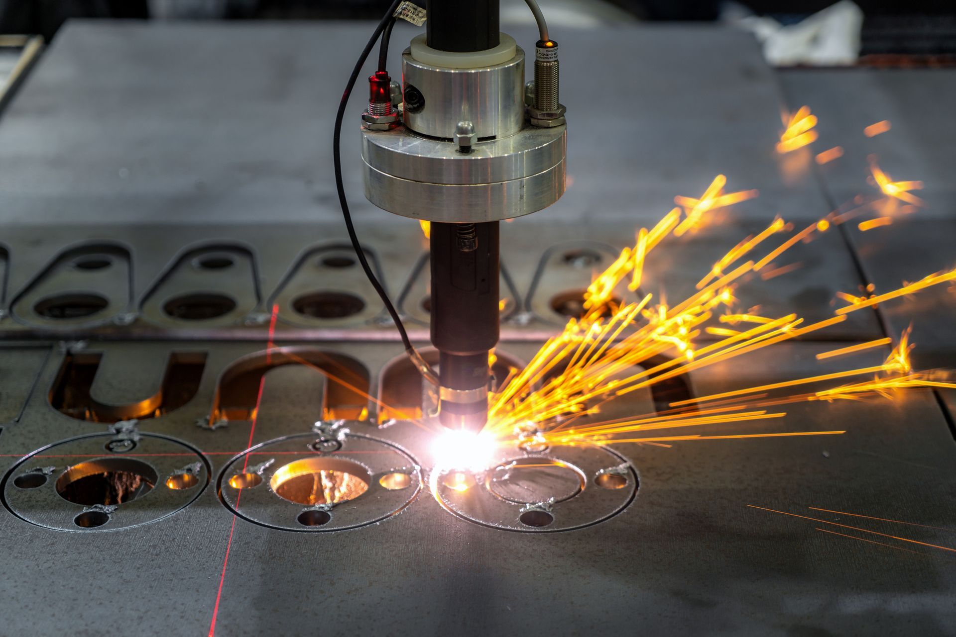 Lamiera tagliata da un laser che emette scintille. Ambiente industriale.