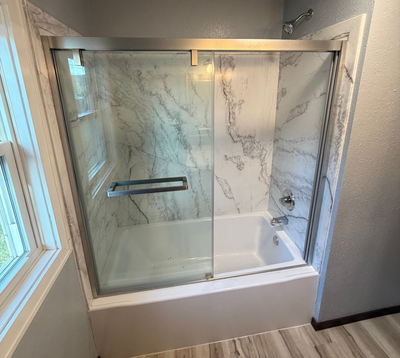 Modern bathroom with a glass-enclosed shower-tub combo and marble-look walls