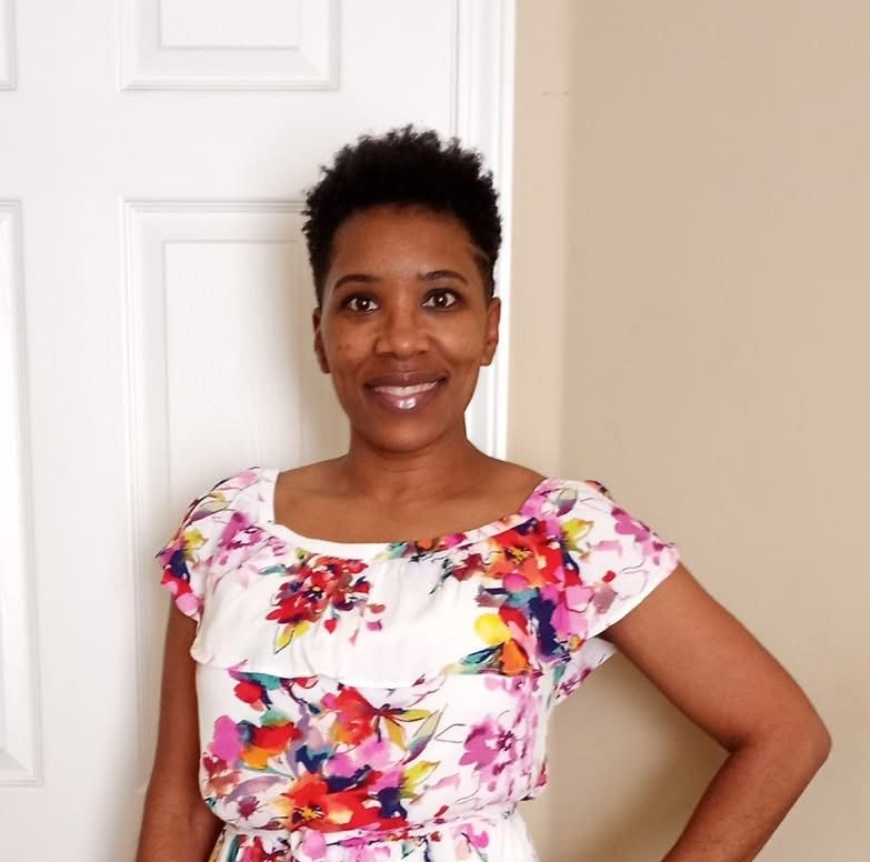 Danielle Gillespie, smiling, wearing a floral dress.