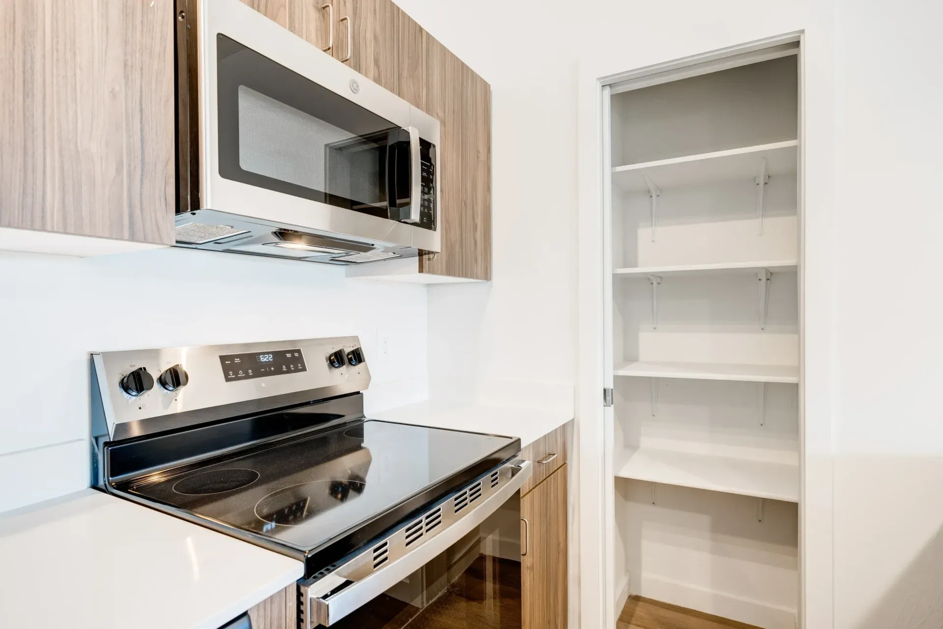 Kitchen with stainless steel microwave above range and a tall pantry closet.
