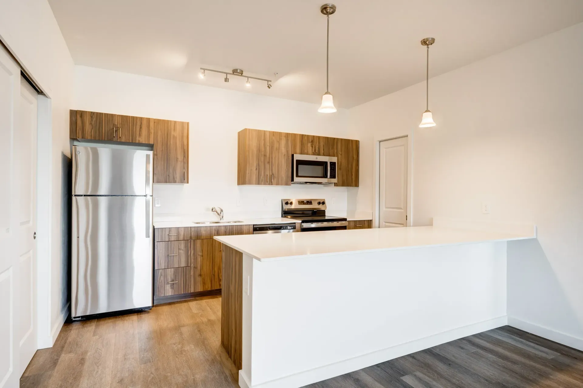 Bright modern kitchen with stainless-steel appliances, wood cabinets, and a large white island.