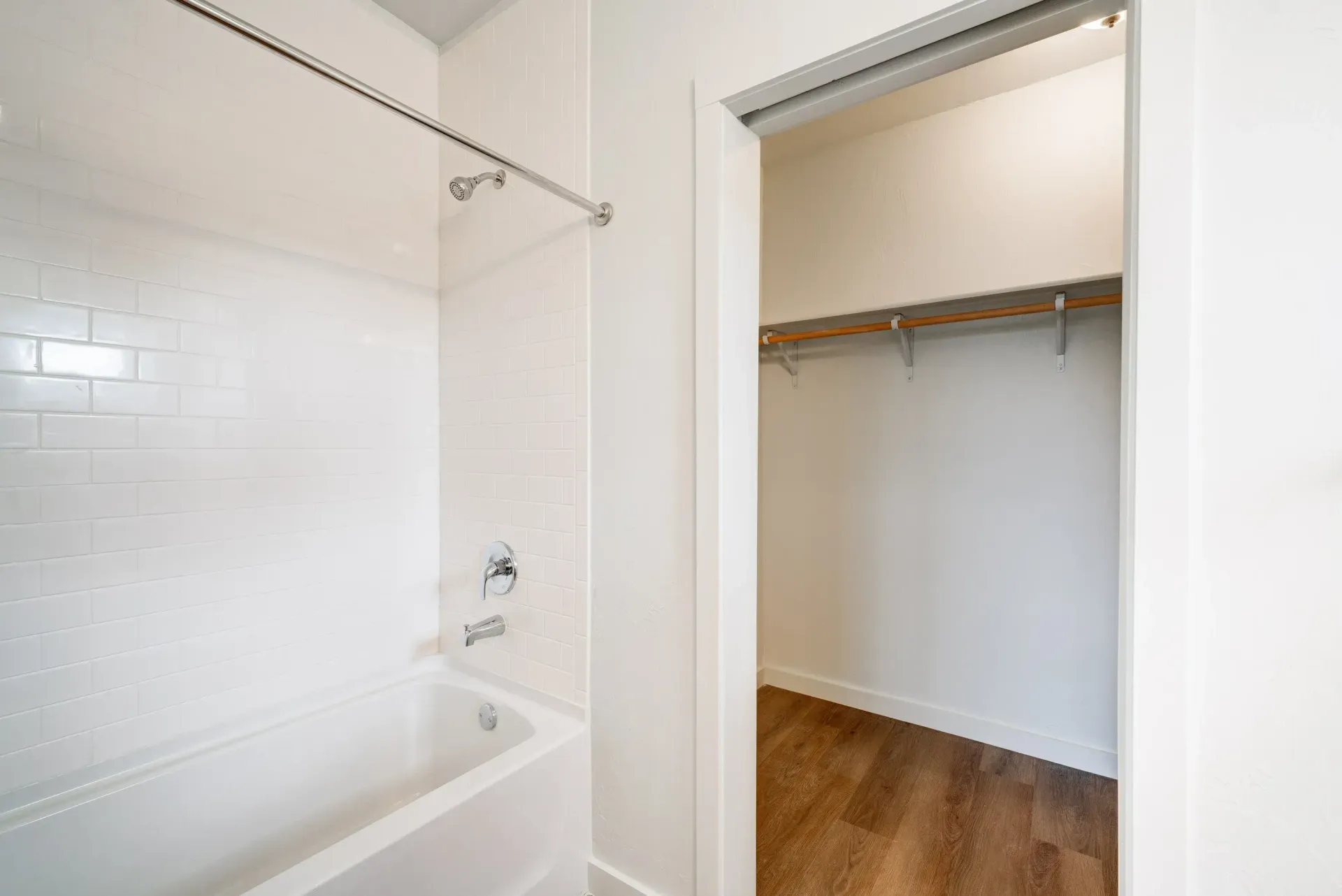 White-tiled bathroom with a bathtub and an open walk-in closet.