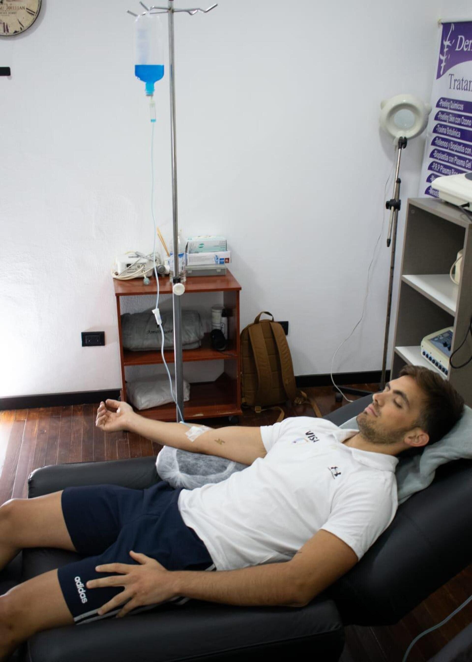 Una persona tumbada en una silla médica recibiendo fluidos intravenosos