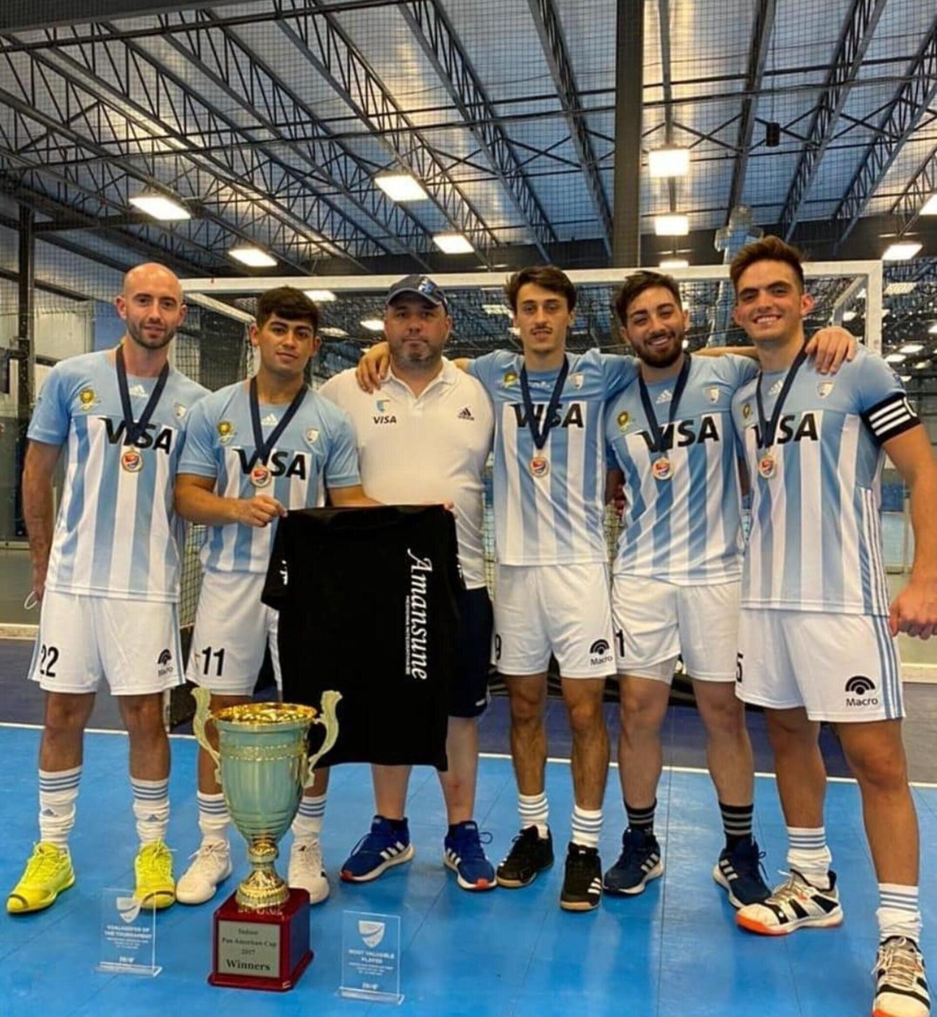 Un equipo con camisetas de rayas azul claro posa en una cancha cubierta con un trofeo y una camiseta negra