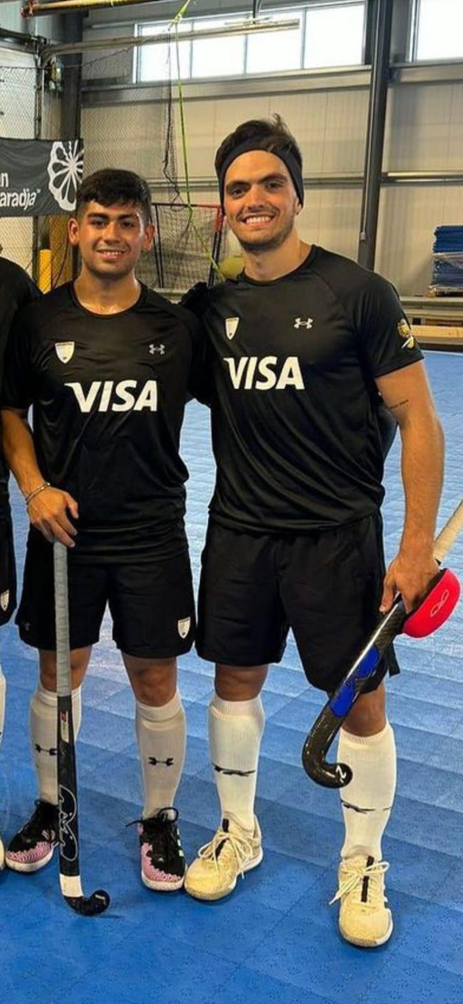 Dos jugadoras de hockey sobre césped, con uniformes negros idénticos y la palabra
