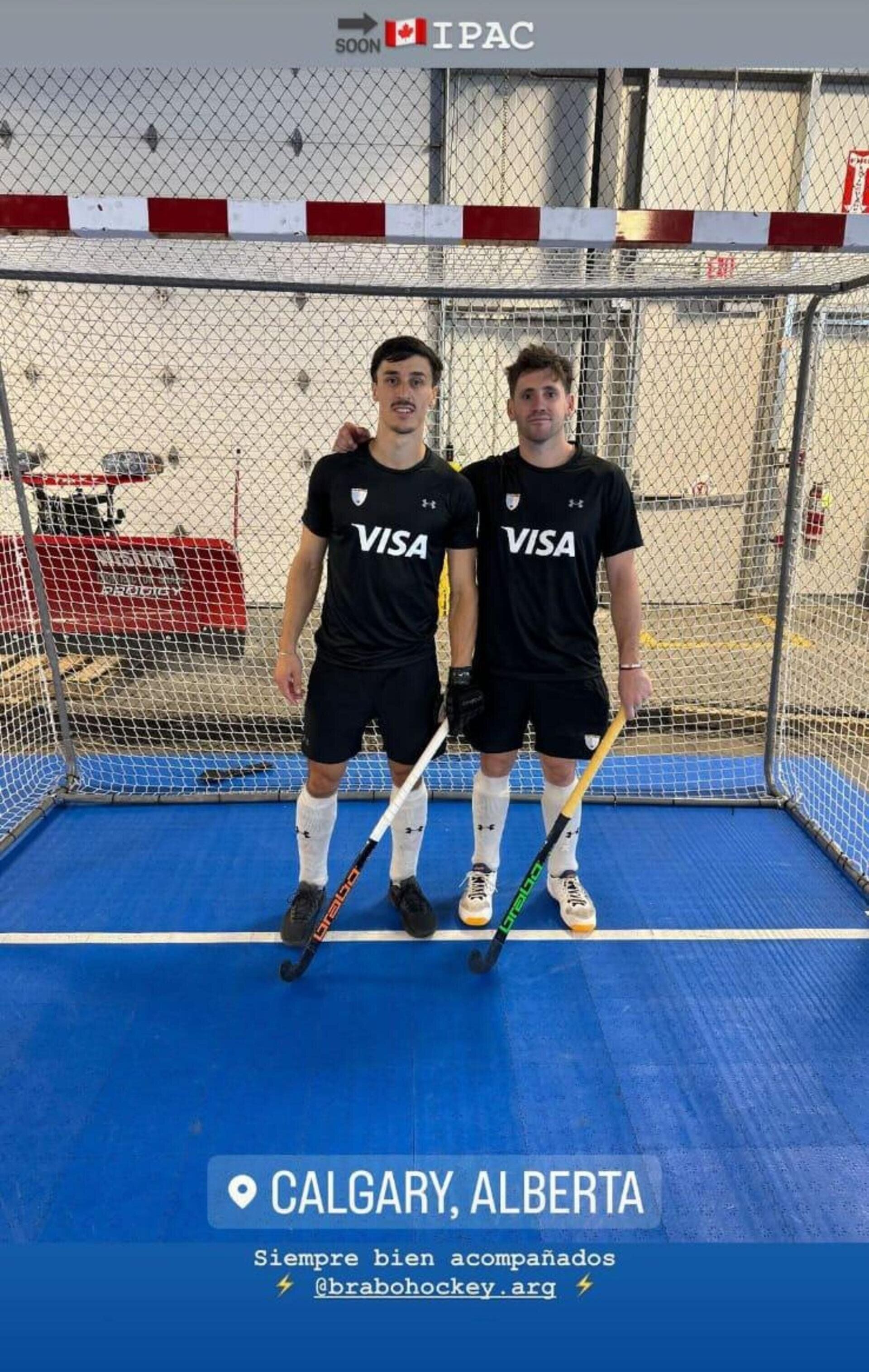 Dos jugadoras de hockey sobre césped, vestidas con uniformes negros de Visa, se encuentran u