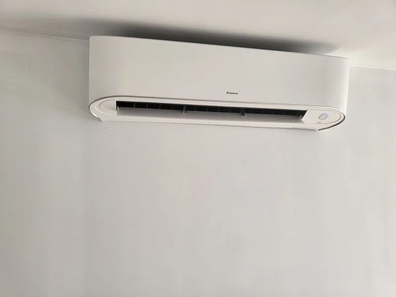 White air conditioner mounted on a light gray wall.