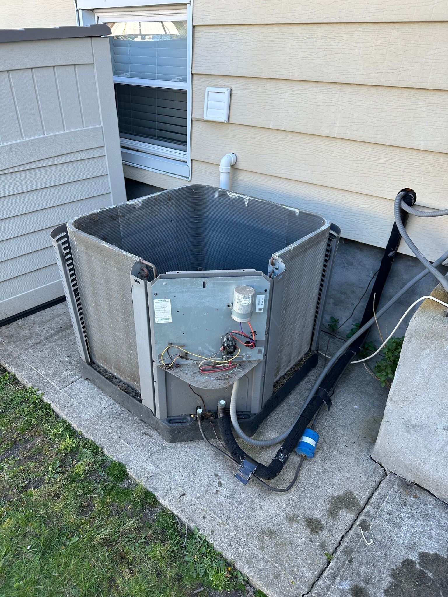 An outdoor air conditioning unit with exposed components, on a concrete pad.