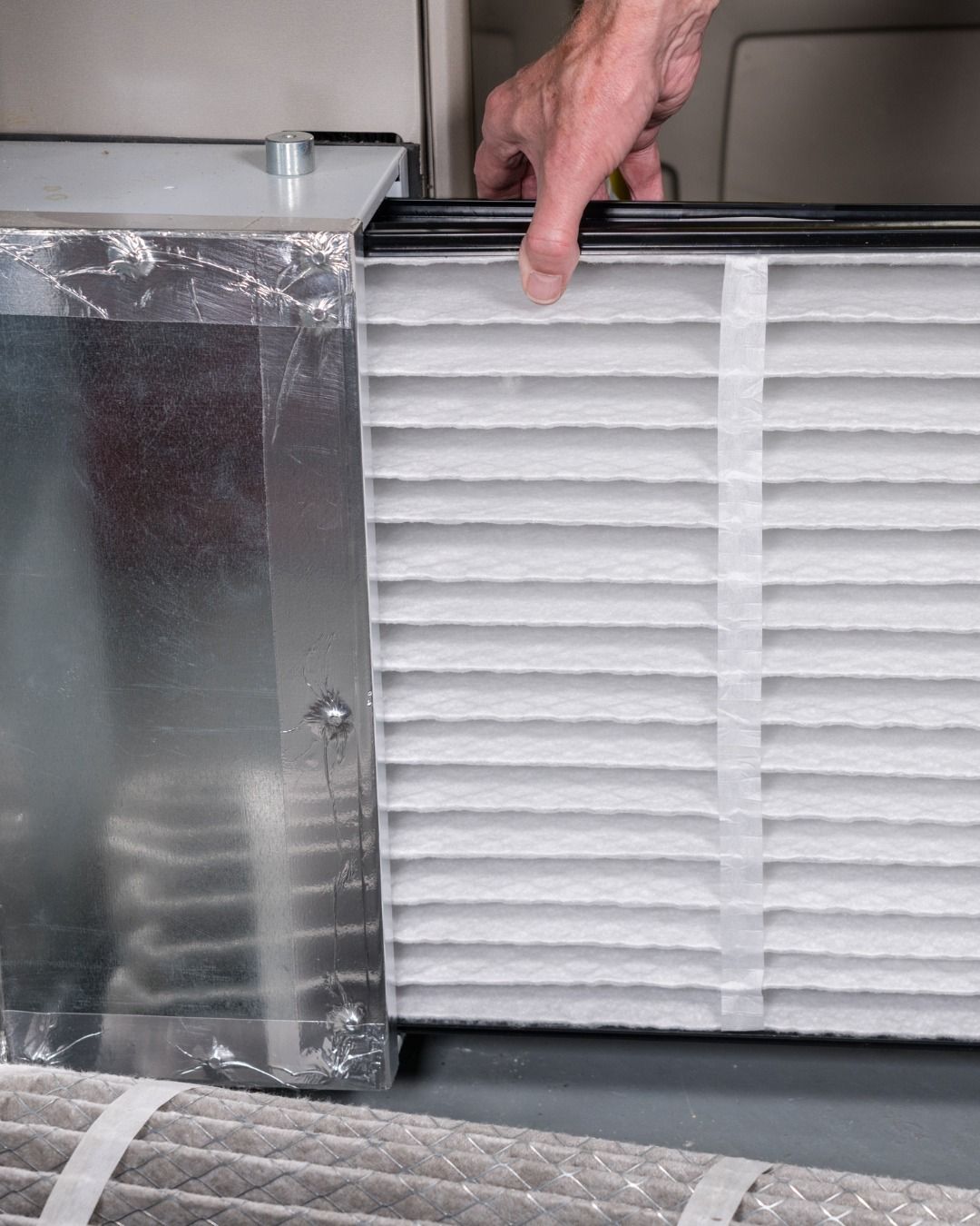 Person replacing a dirty air filter in a furnace.