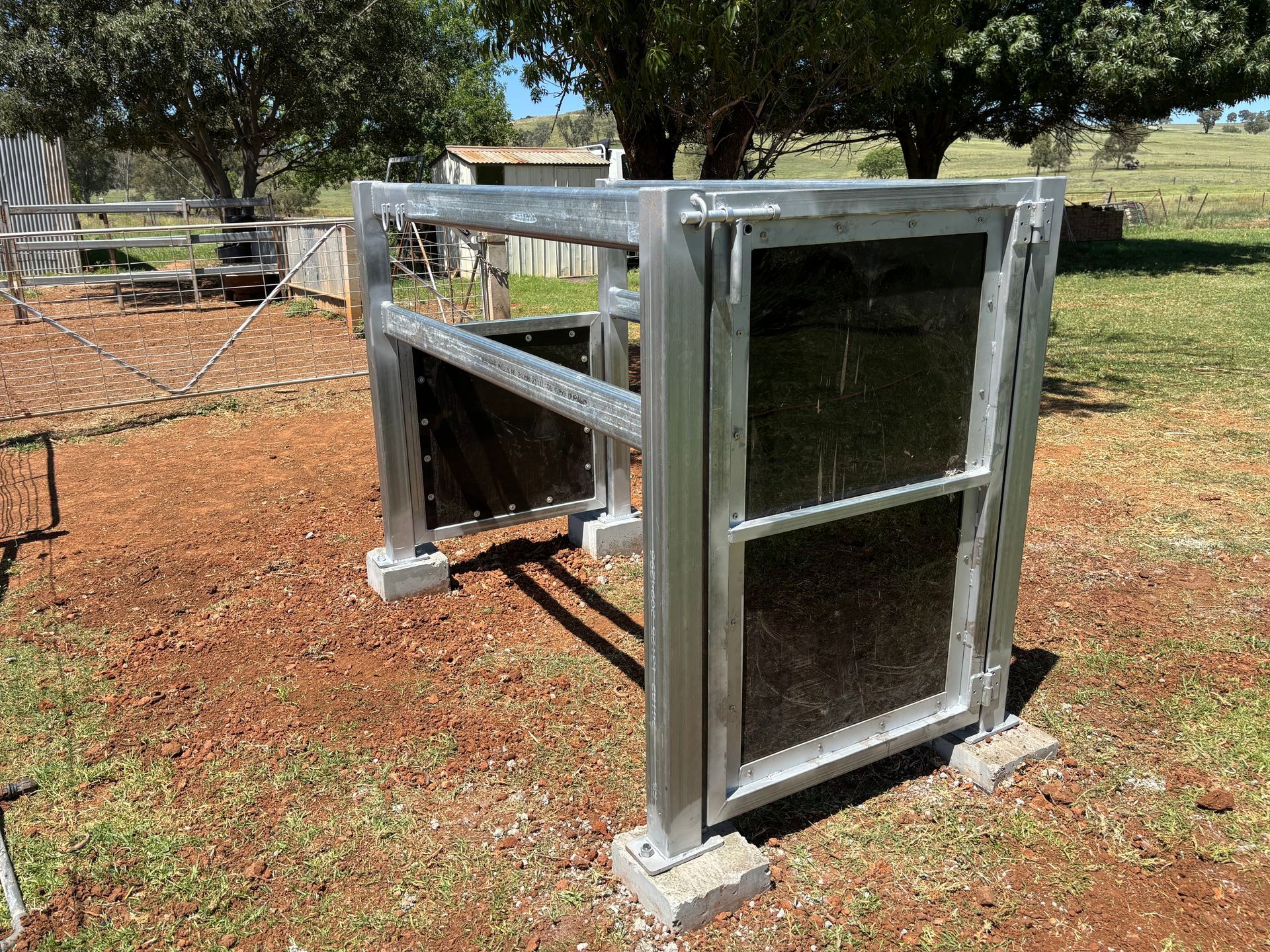 Metal livestock gate, on concrete blocks, outdoors.