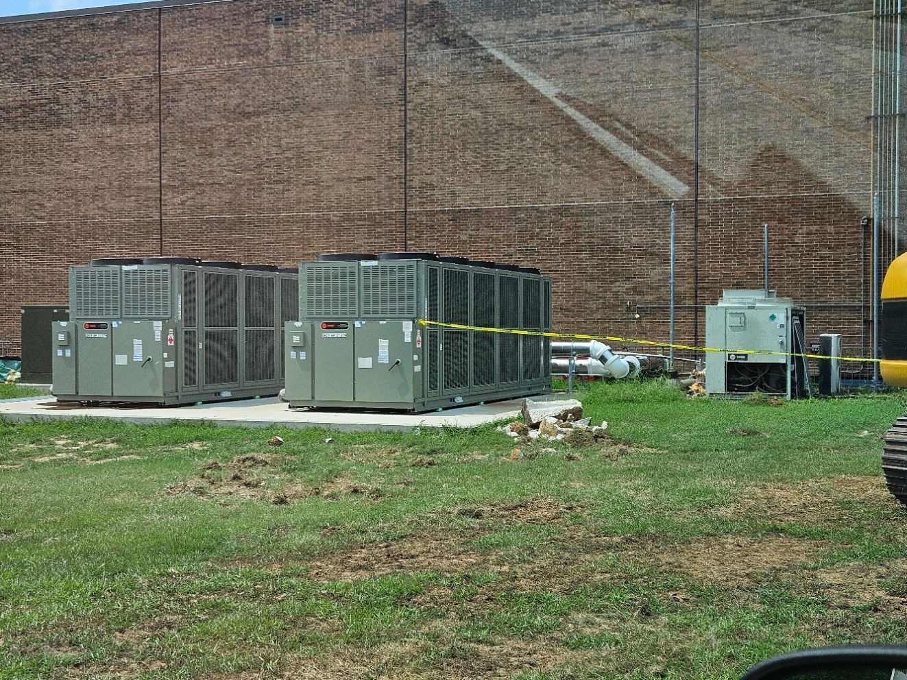 A row of air conditioners are sitting in a grassy field.