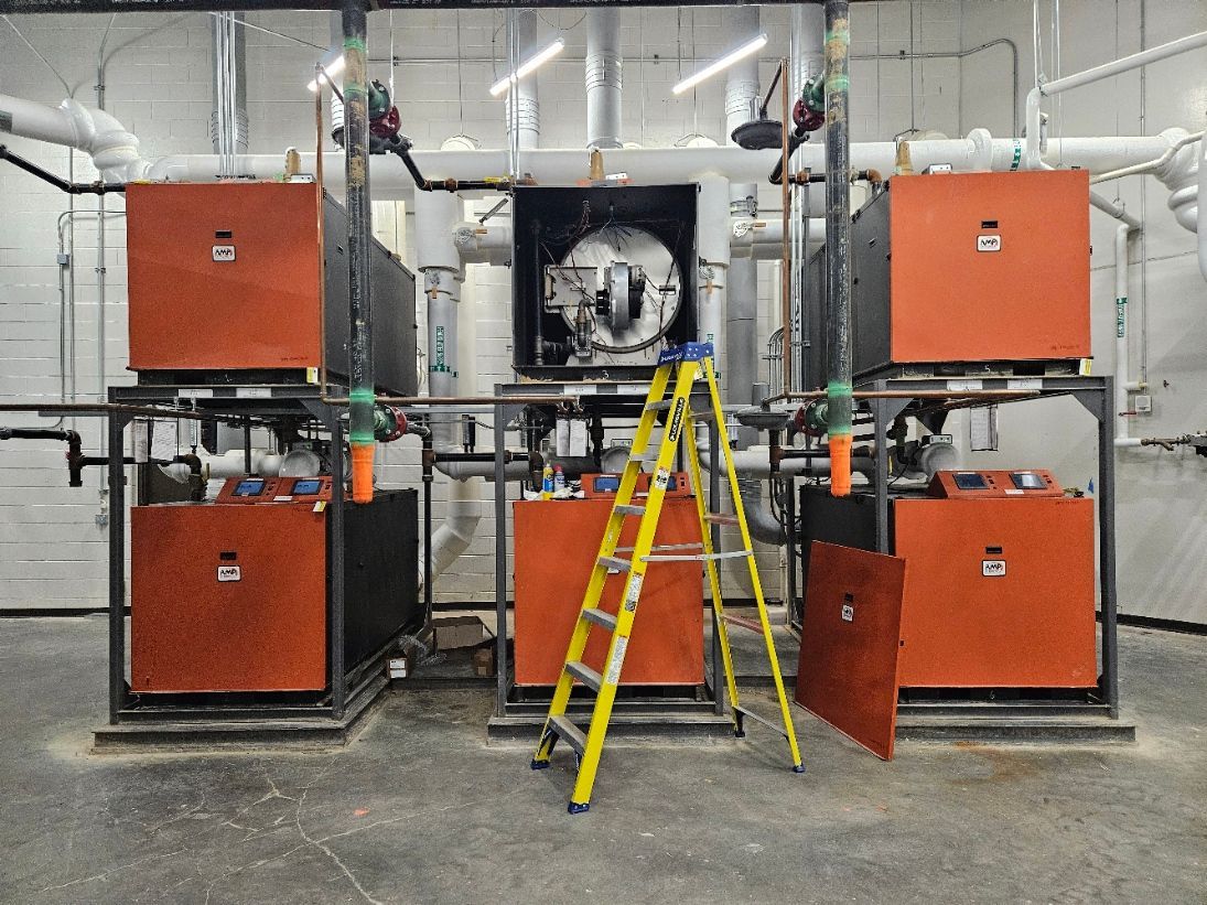 A ladder is sitting in front of a row of boilers.