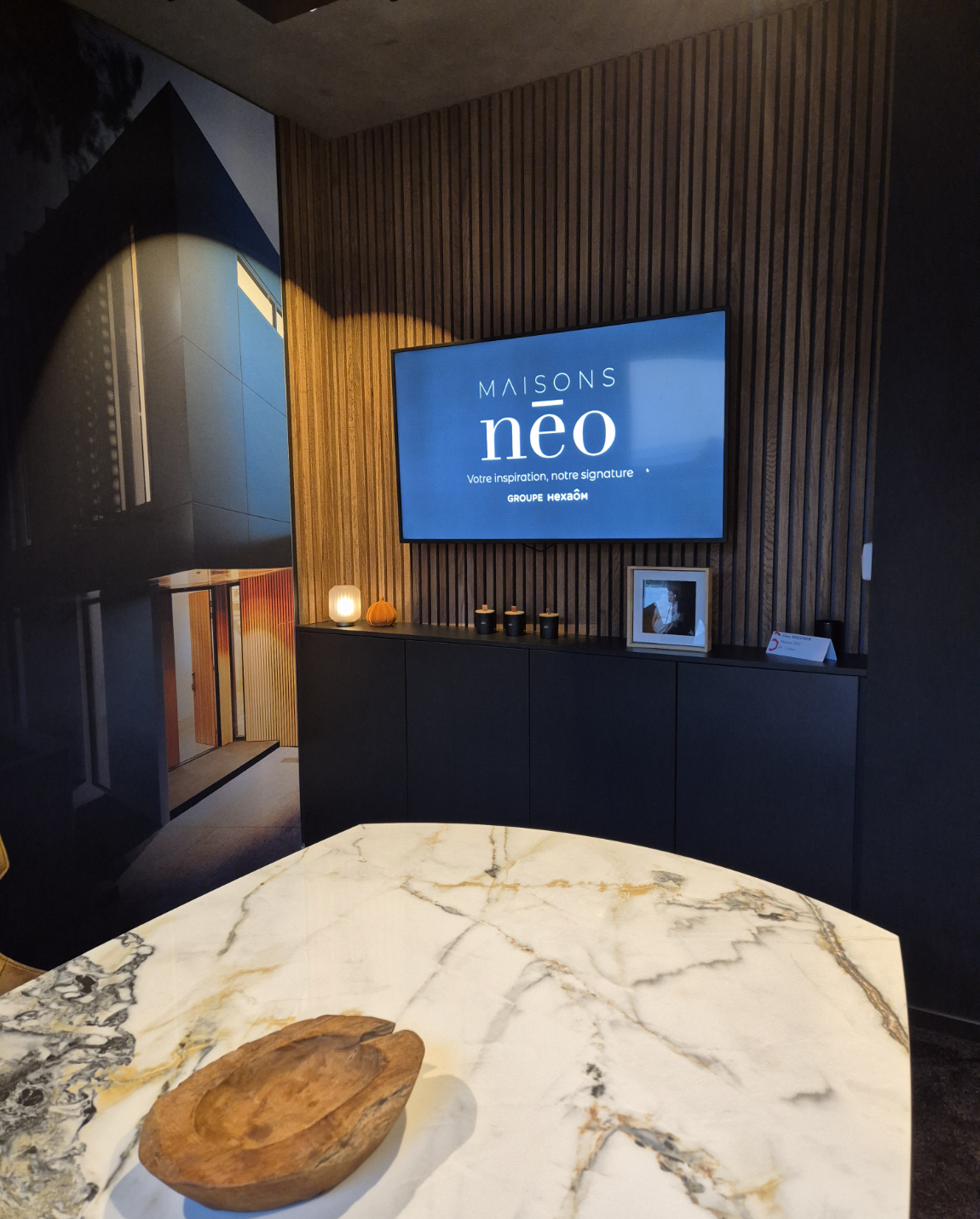 Interior with TV on a dark cabinet against a wood-paneled wall, a marble table with a bowl in the foreground.