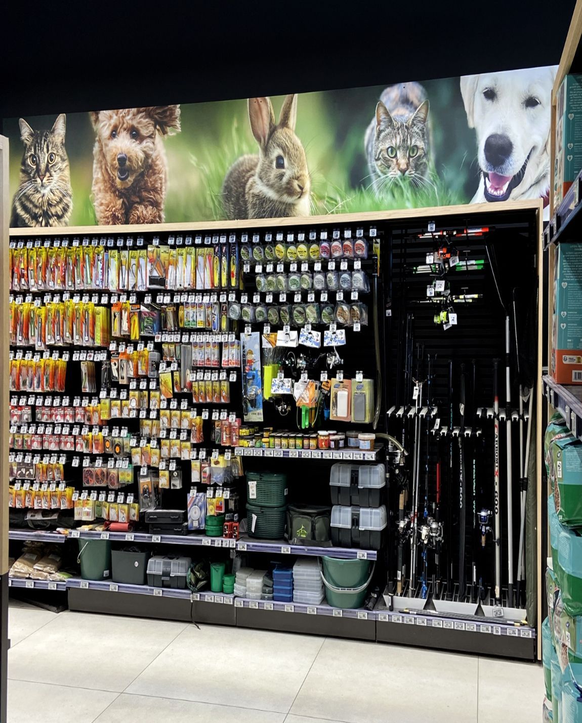 Allée d'une animalerie avec des rangées d'accessoires pour chiens et de laisses sous des photos d'animaux sur la bannière supérieure
