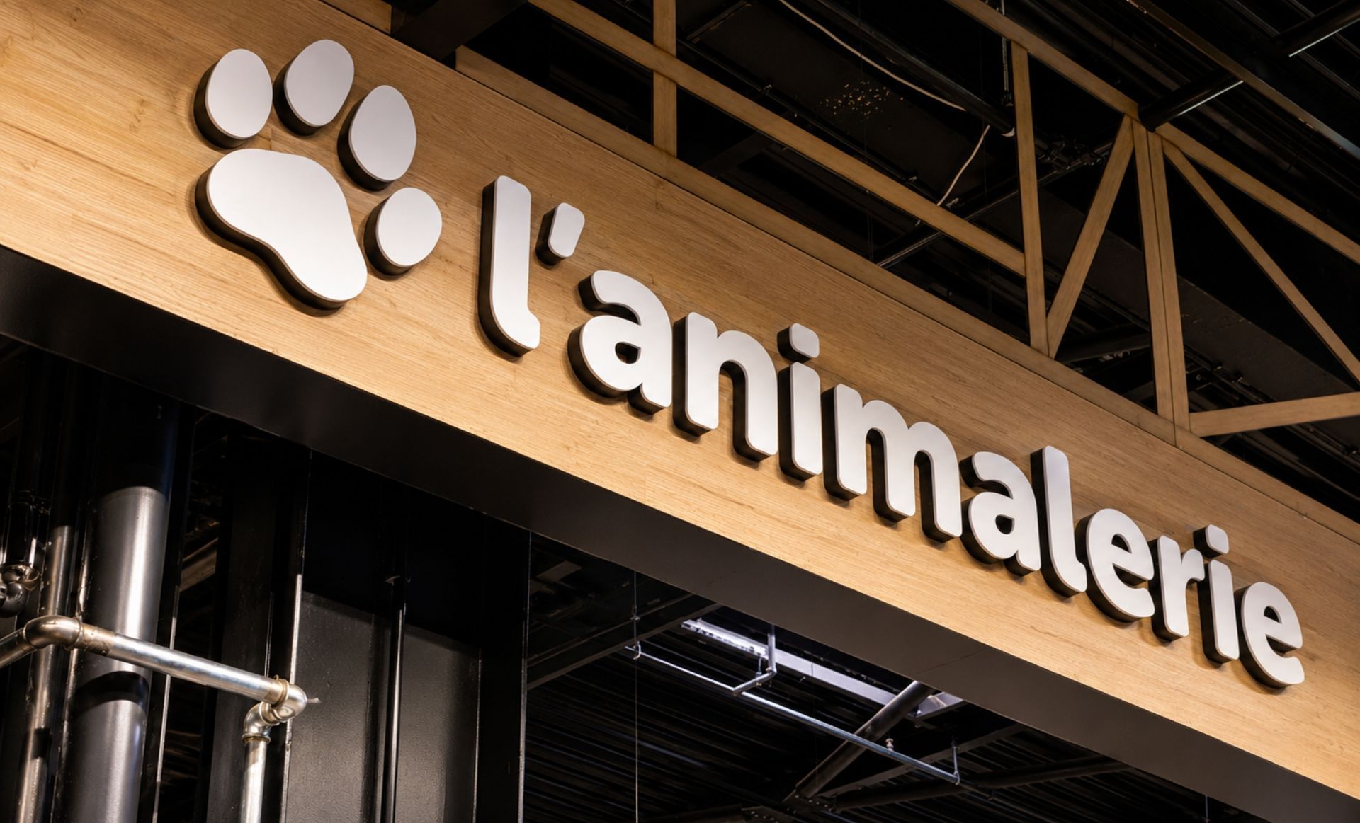 Enseigne en bois du magasin indiquant « l'animalerie » avec un logo en forme d'empreinte de patte au-dessus.