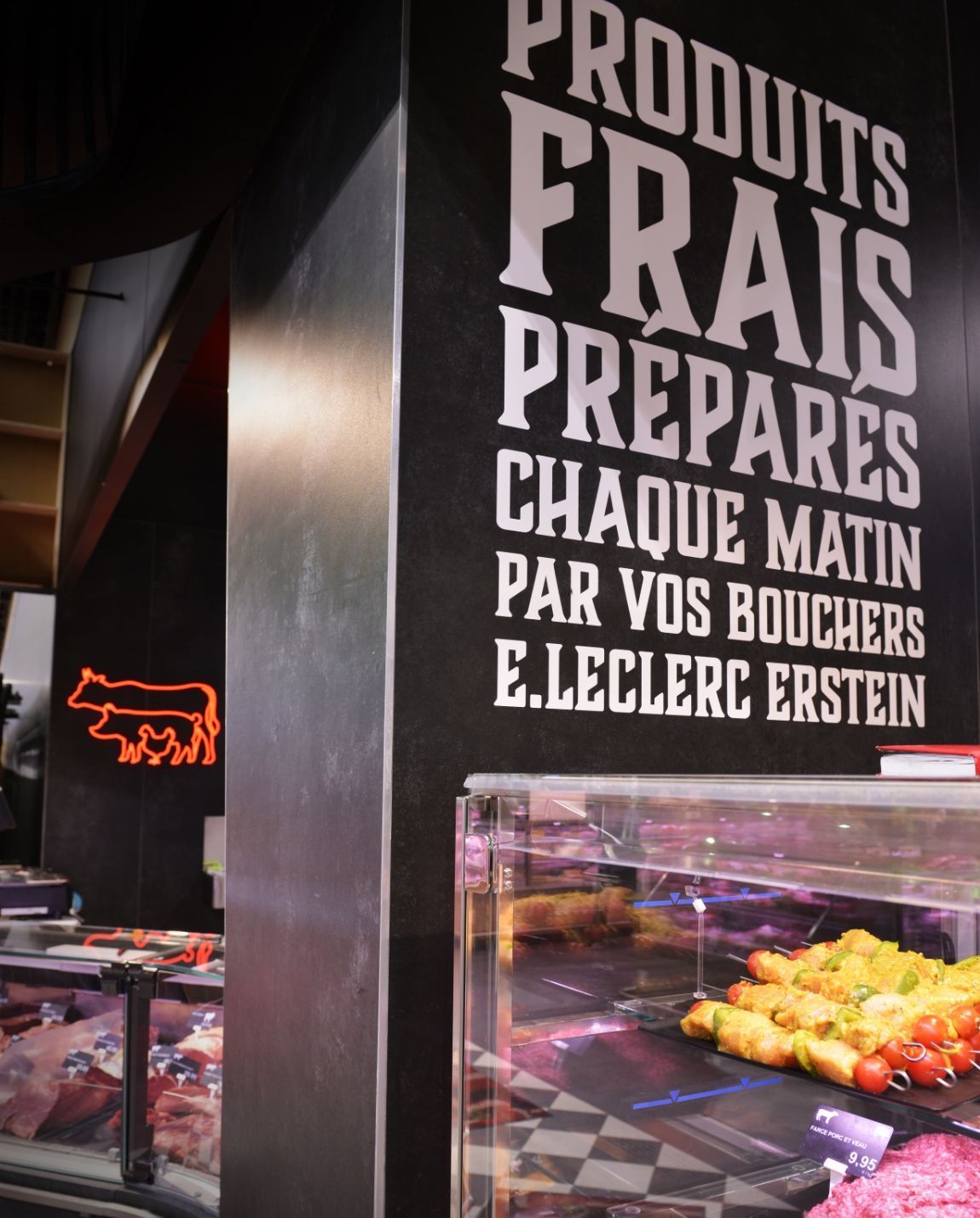 Vitrine de boucherie avec enseigne française indiquant les produits frais et les viandes préparées, à côté d'une vitrine réfrigérée.