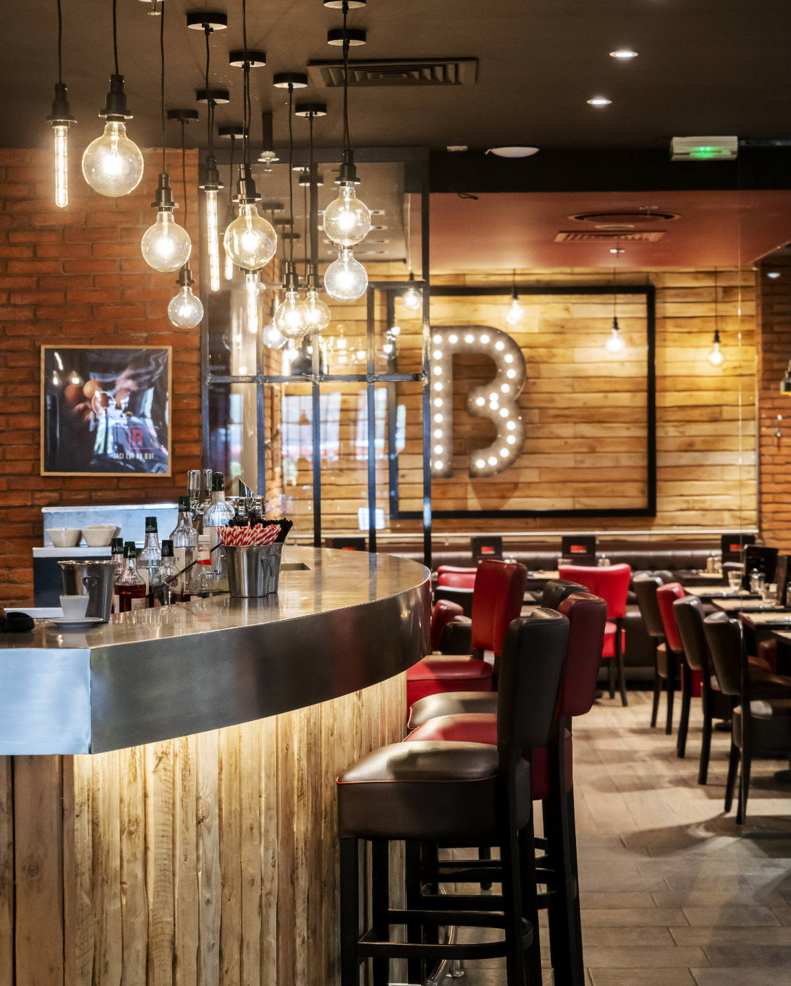 Restaurant interior with bar stools, exposed brick, and a lit-up 