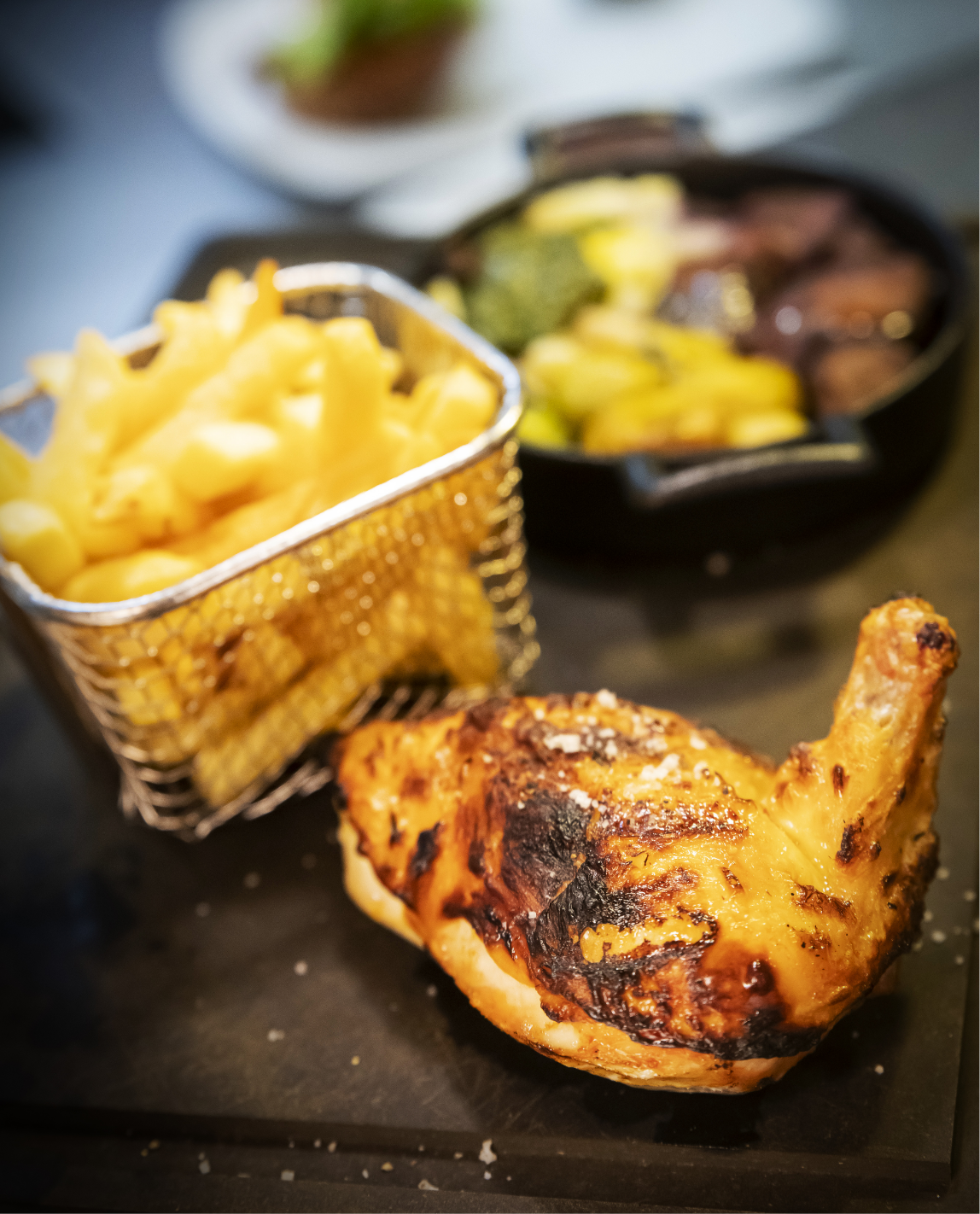 Grilled chicken leg with fries in a basket, plus sauteed vegetables.