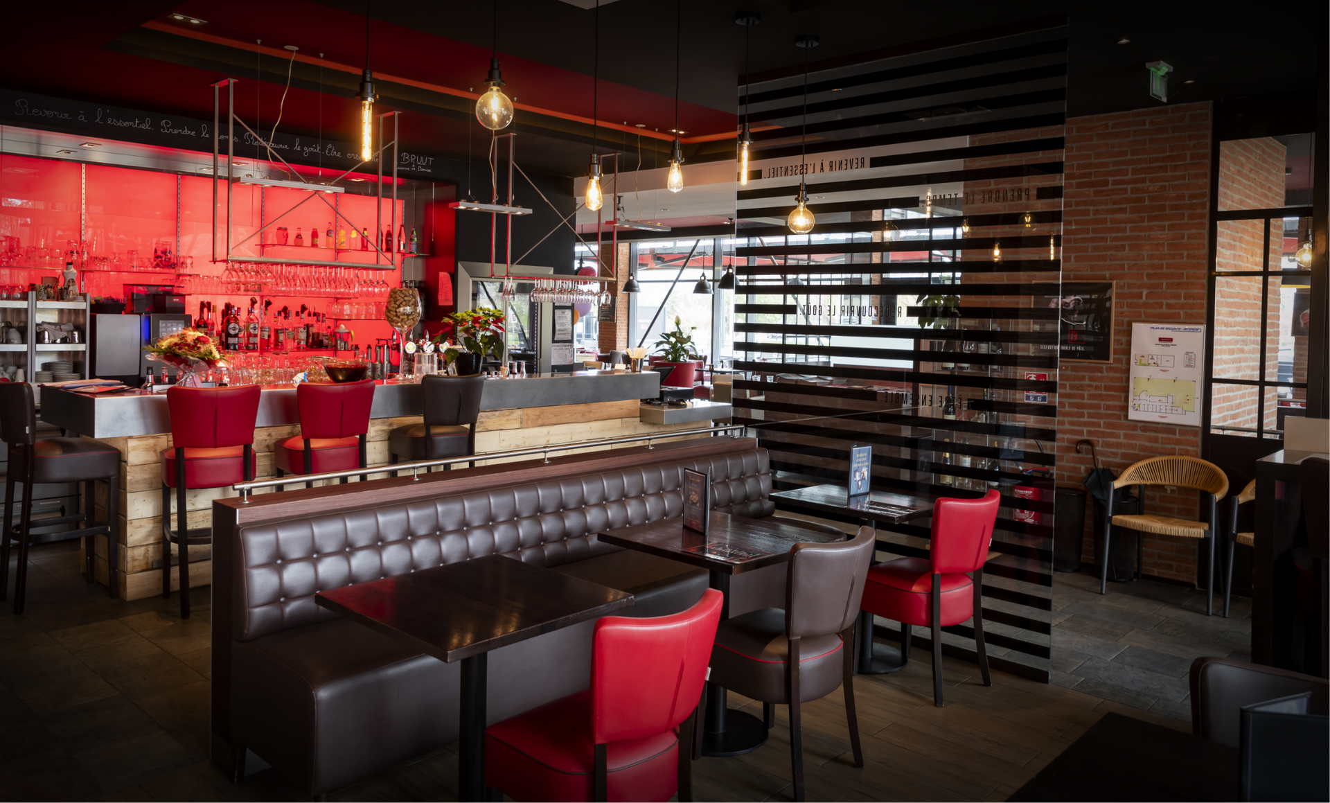 Interior of a restaurant with a bar and seating area; red and brown decor.