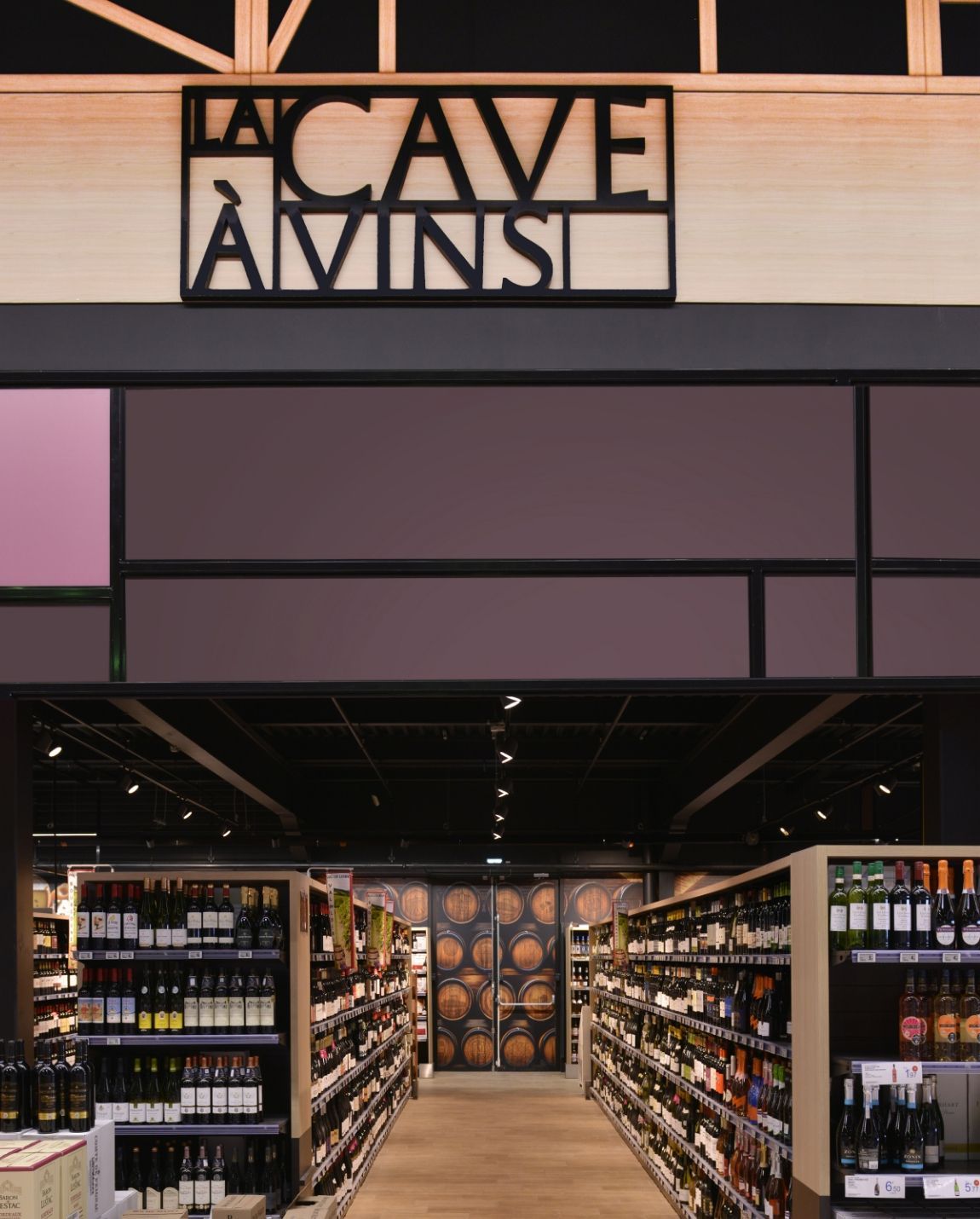 Entrée de la boutique de vins Cave Vinis avec des rangées de bouteilles et une façade sombre et moderne.