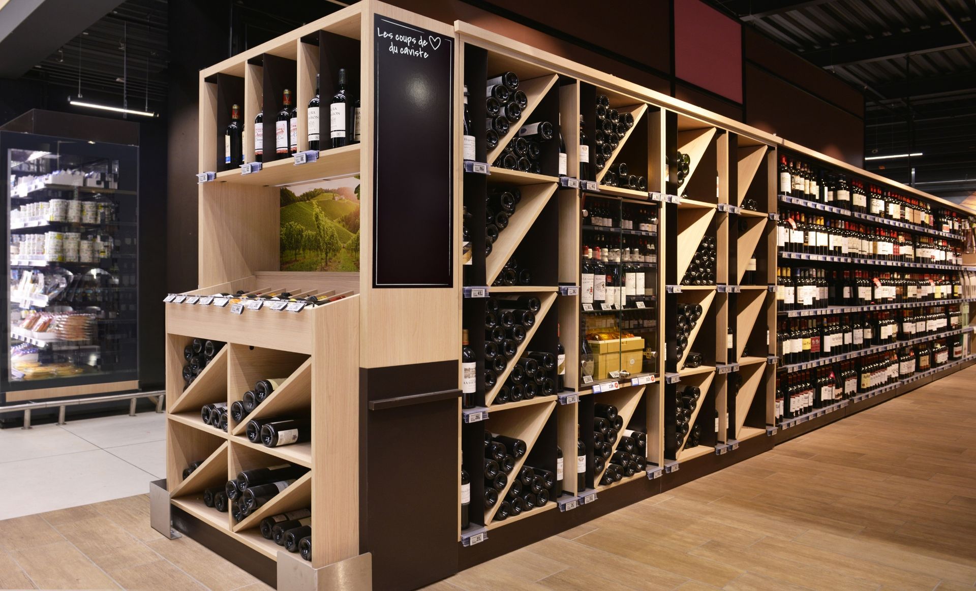 Allée moderne d'une cave à vin avec des étagères en bois et des rangées de bouteilles de vin sous un éclairage chaleureux
