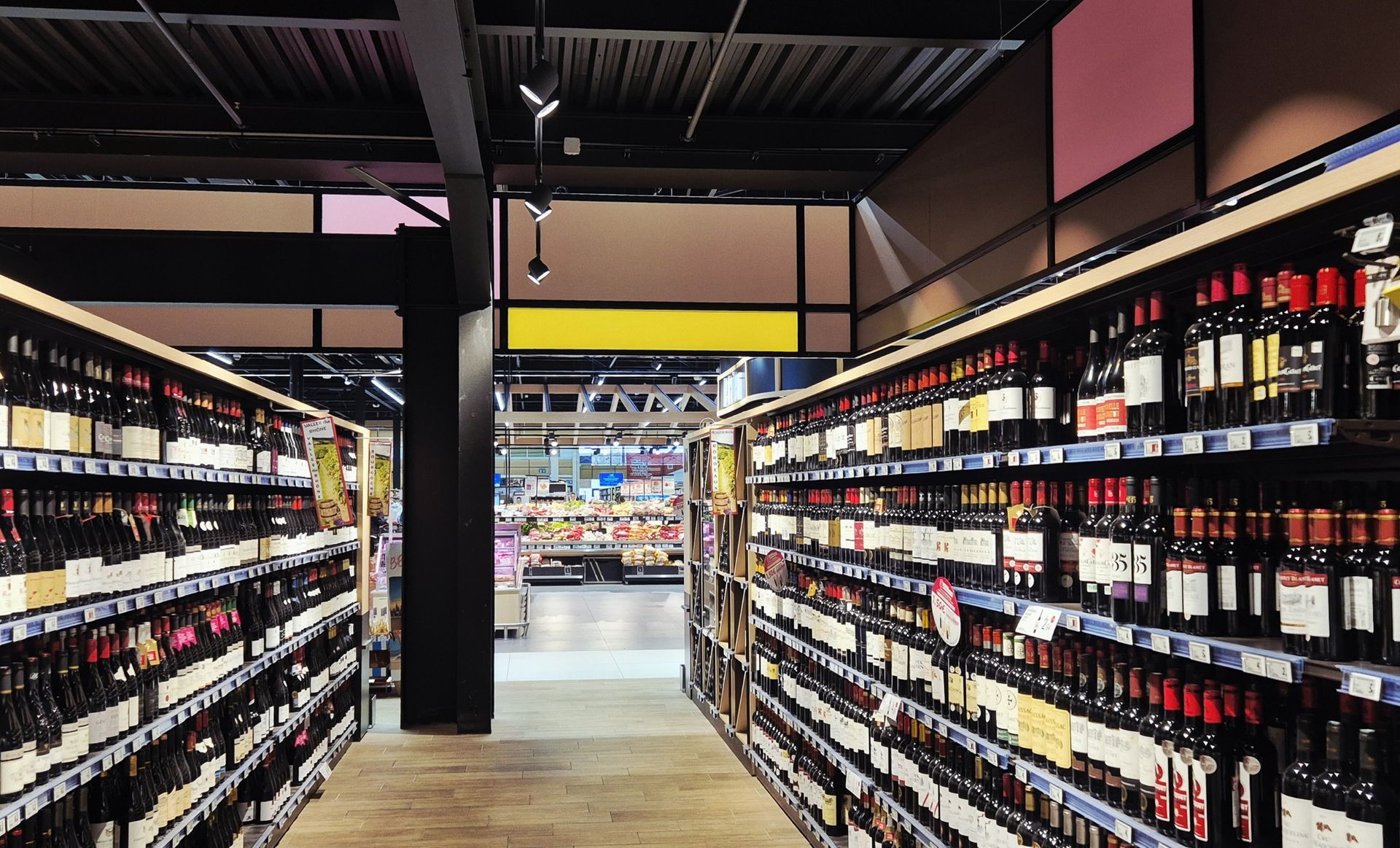 Allée moderne d'une cave à vin avec des étagères en bois et des rangées de bouteilles de vin sous un éclairage chaleureux