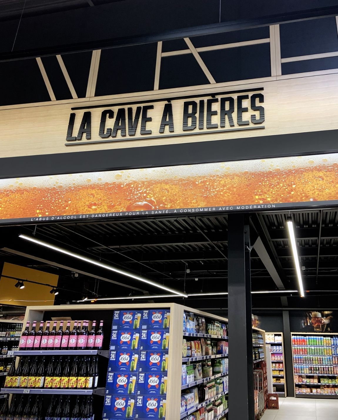 Panneau « LA CAVE À BIÈRES » au-dessus des rayons de bières d'un supermarché
