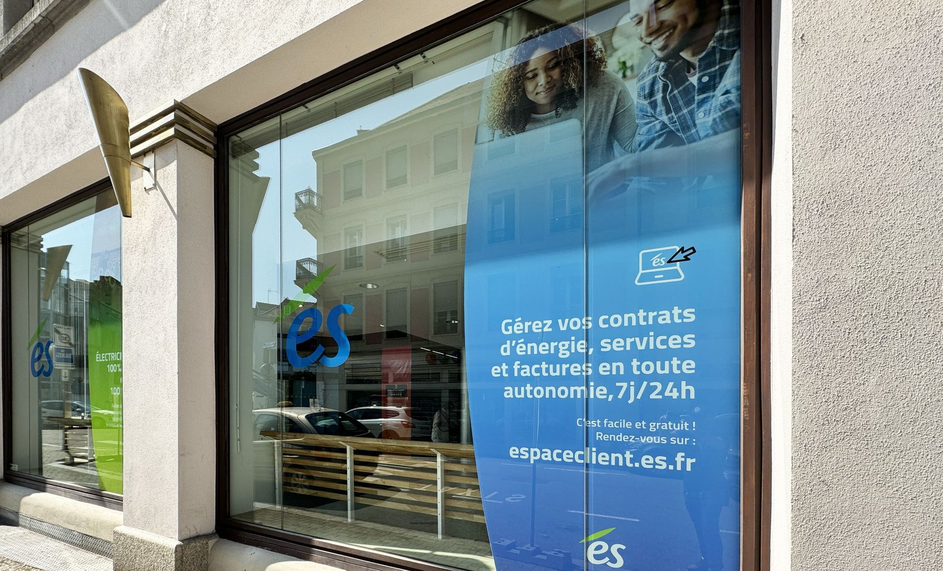 Exterior of a business with a blue sign advertising energy services. Storefront window displays merchandise.