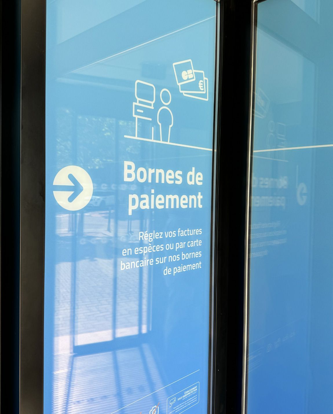 Blue sign indicating payment kiosks. Text and icons in white, arrow points right.