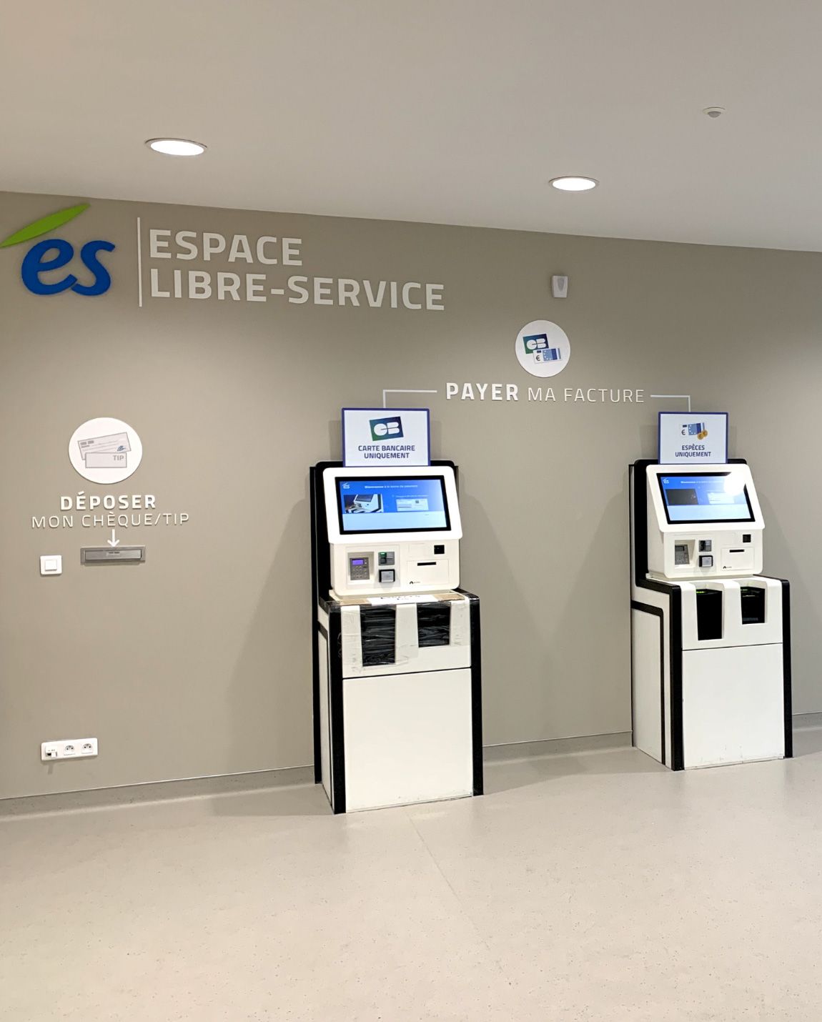 Two white self-service kiosks in a service area, labeled 