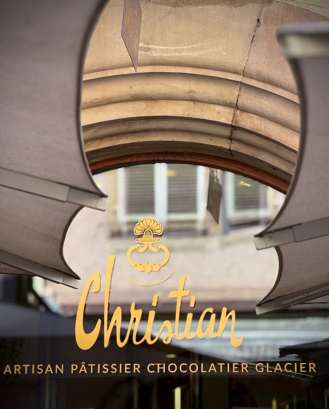 Boutique artisanale de pâtisserie et chocolat, glacier, façade avec texte doré, auvent et détails architecturaux.