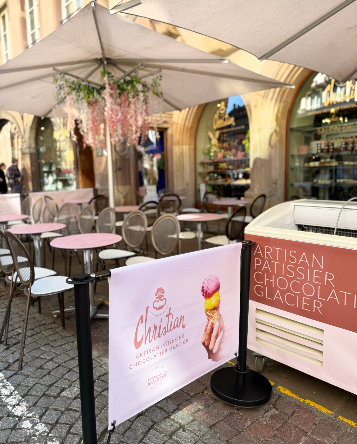 Café en plein air avec des tables et des chaises roses, cathédrale de Strasbourg.