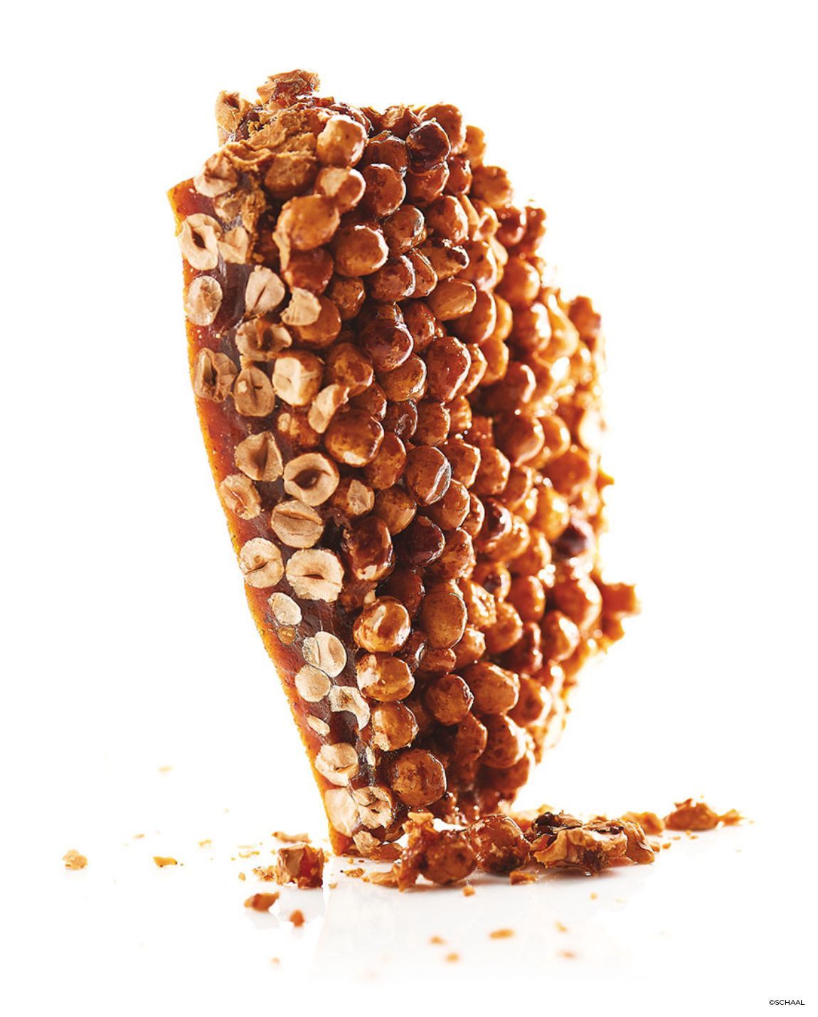 Hazelnut brittle, caramelized sugar, and crushed nuts against a white background.
