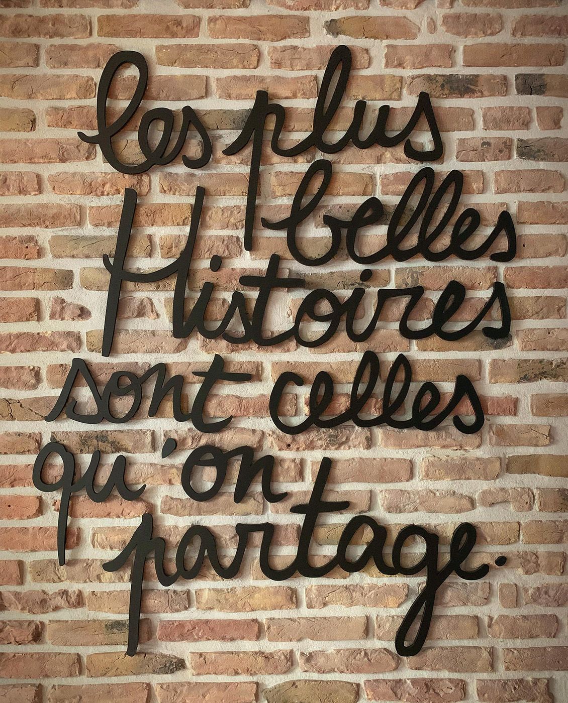 Black cursive text on a brick wall reads, 