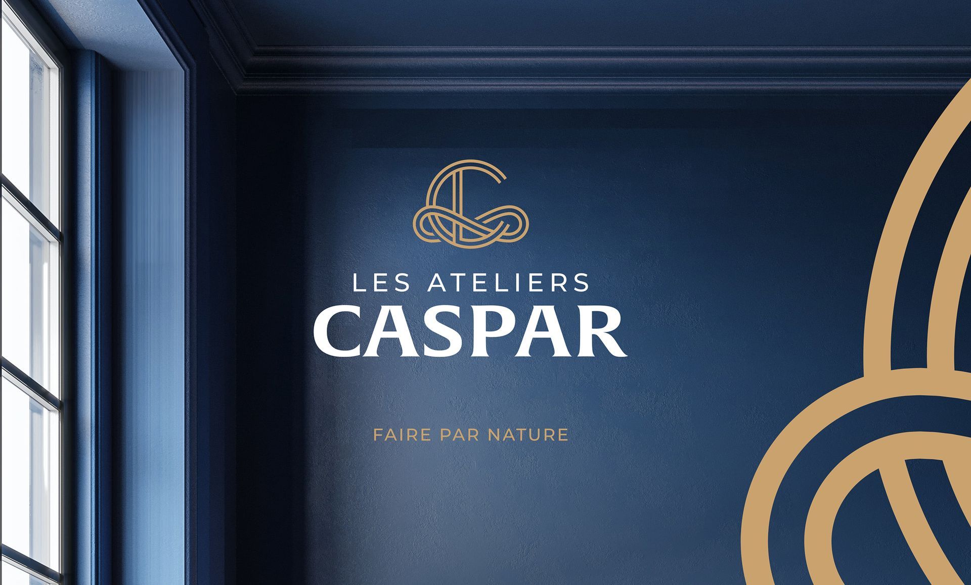 Logo for Les Ateliers Caspar on a dark blue wall with gold decorative design.