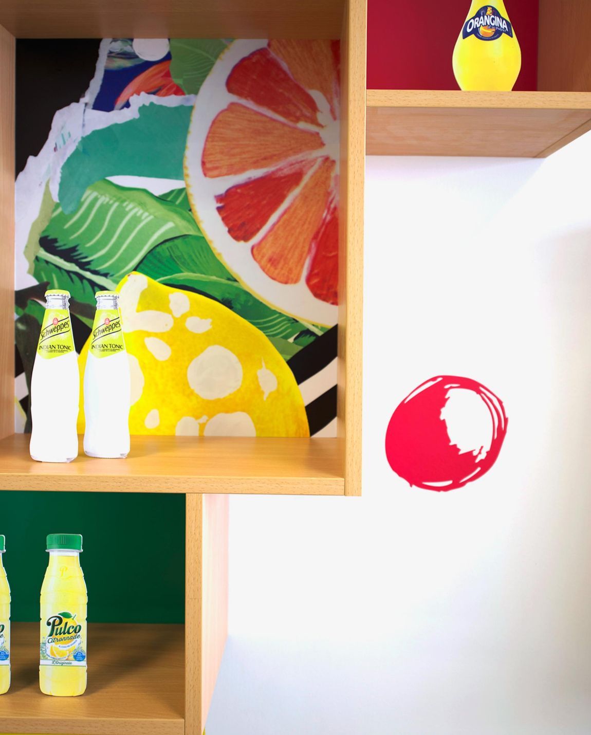 Shelves with citrus-themed art and lemonade bottles. A red circle is on the wall.