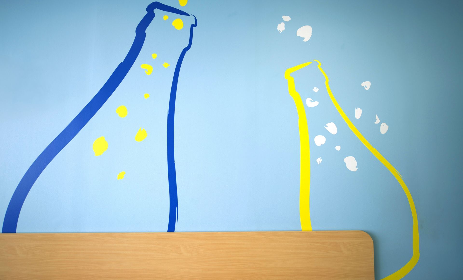 Blue wall with painted bottles, one yellow and one blue, with bubbles.