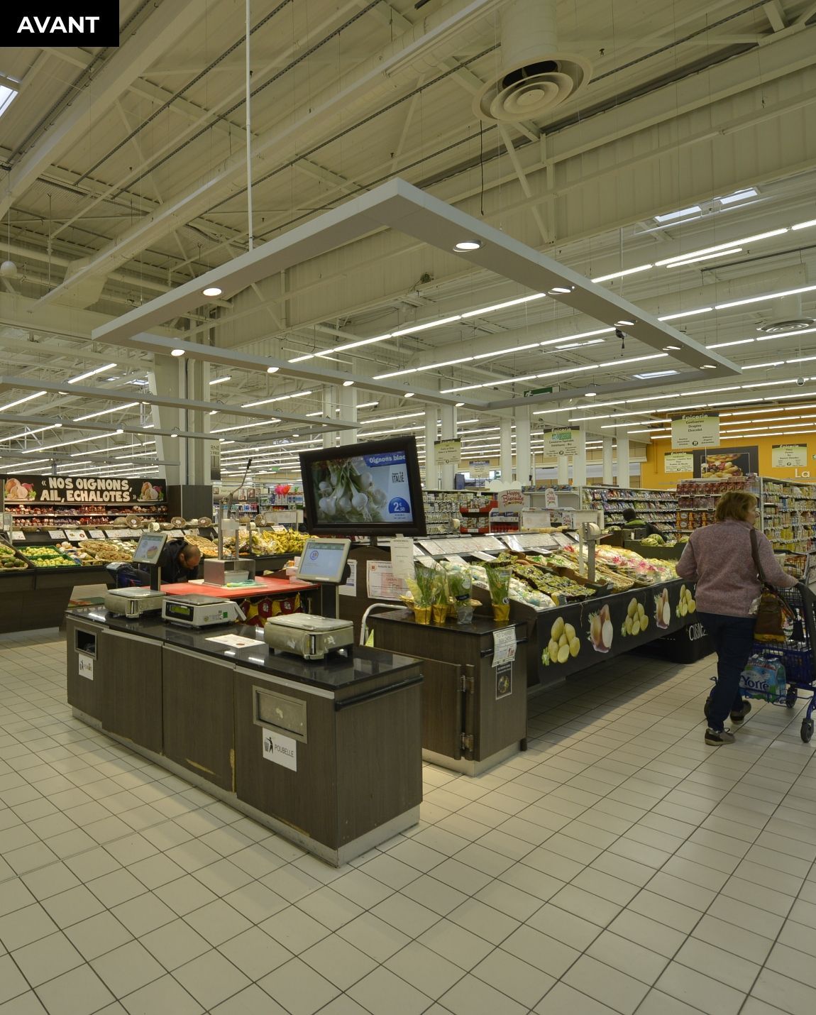 AVANT TRAVAUX Présentoir de produits frais de supermarché avec des étagères de fruits et une petite table ronde devant