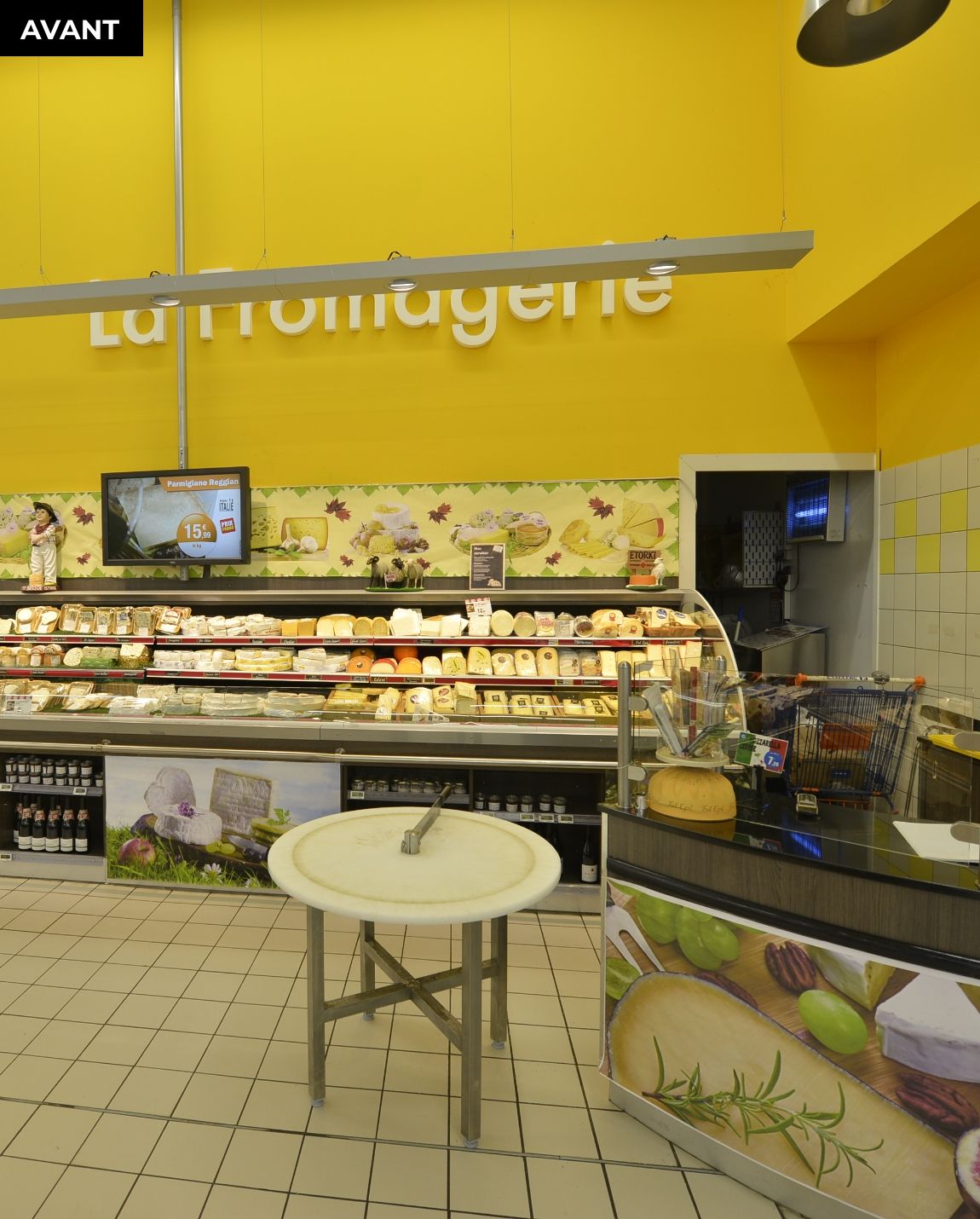 AVANT TRAVAUX Présentoir de produits frais de supermarché avec des étagères de fruits et une petite table ronde devant