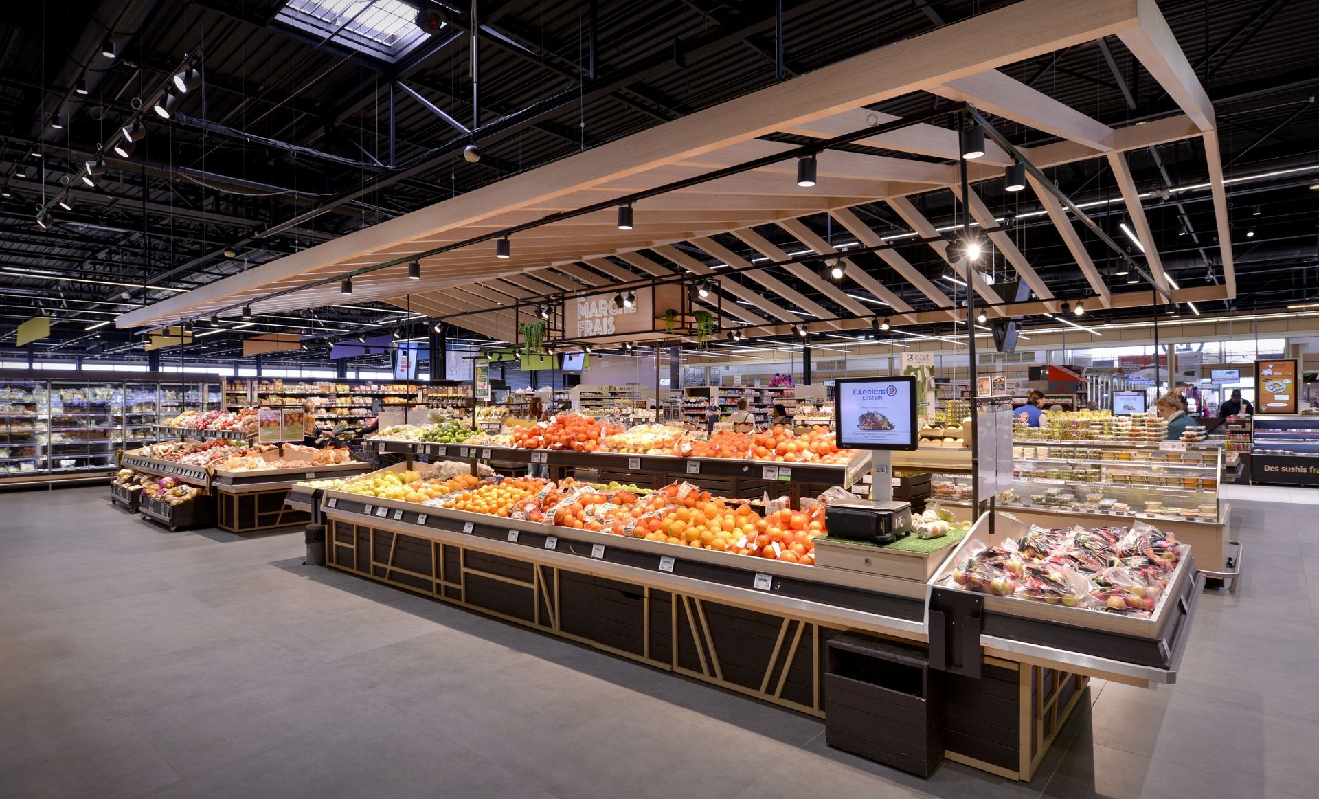 Rayonnage de fruits et légumes et de produits de la mer en supermarché, avec éclairage vif et longs comptoirs réfrigérés.