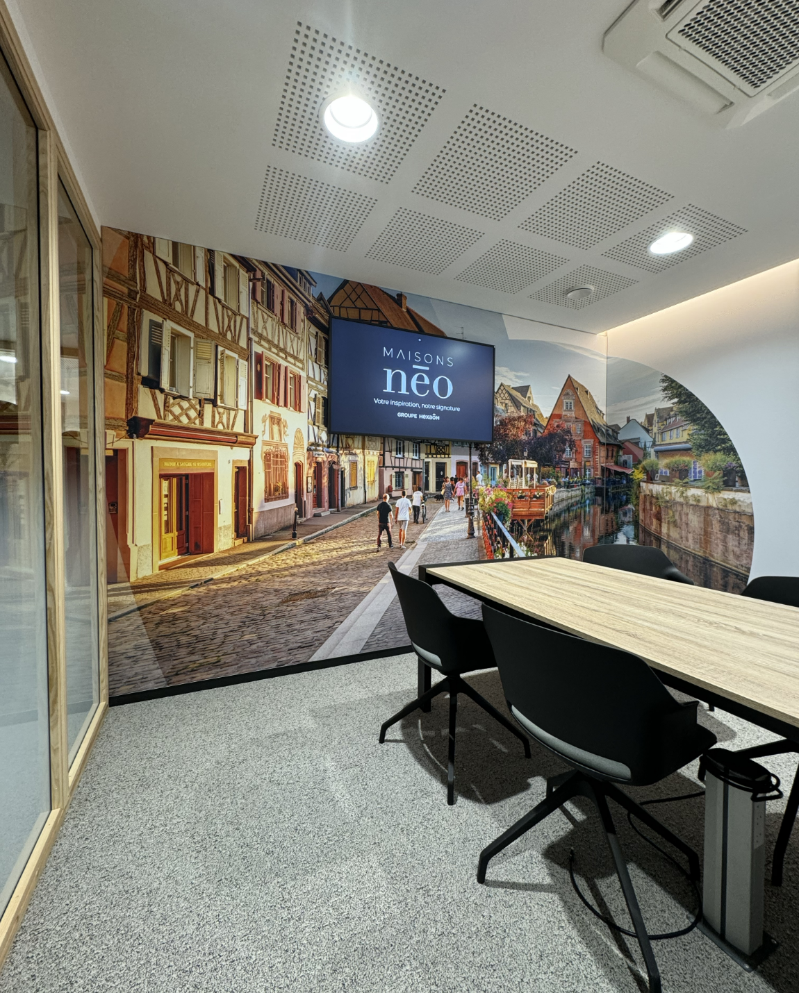 Conference room with a long table, black chairs, and a wall mural of a European street scene.