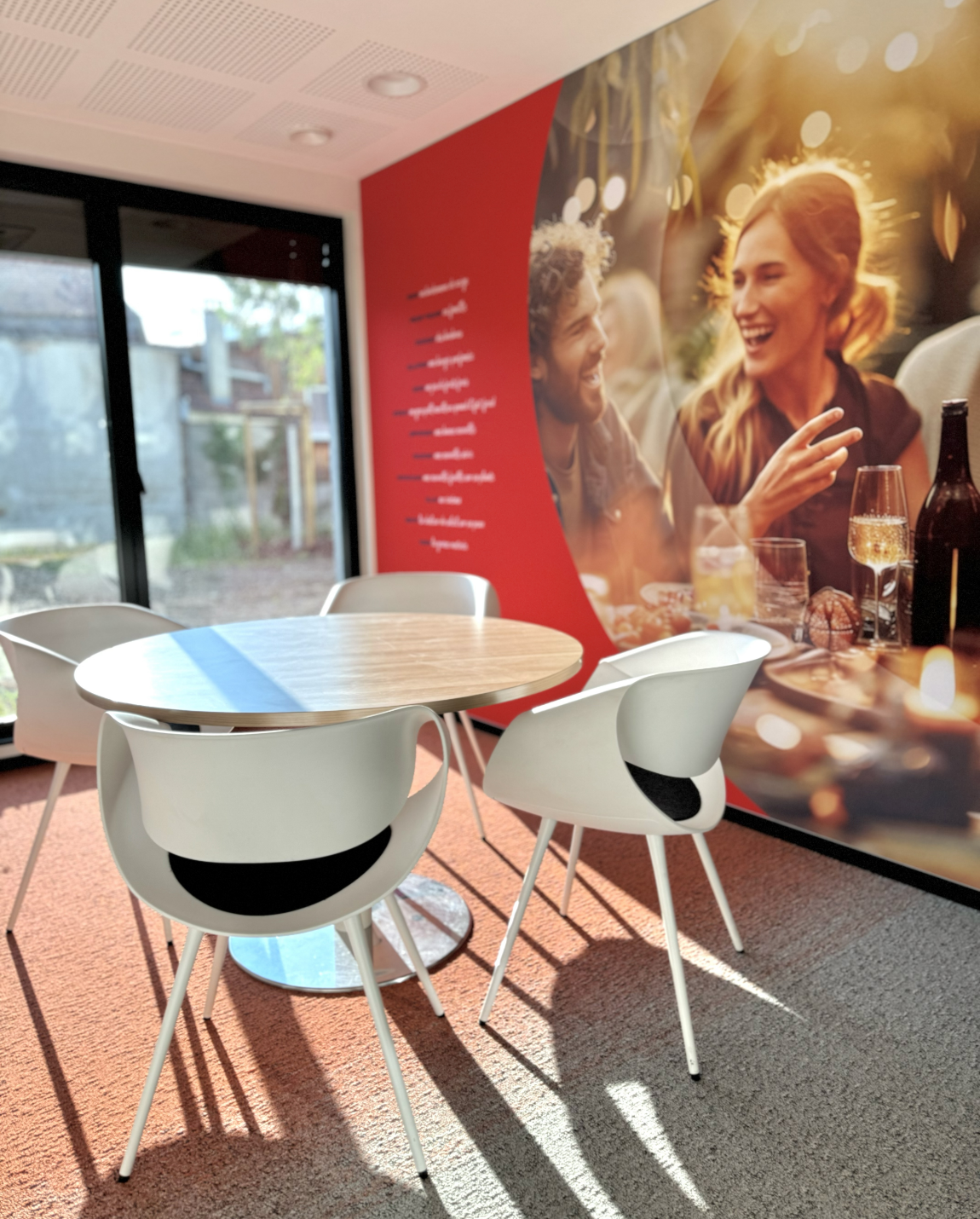Interior with table and chairs in front of a wall with a graphic of people dining outdoors.