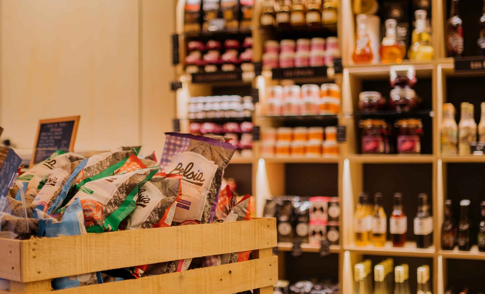 Wooden crate filled with snack bags in front of shelves stocked with various food products in a store.