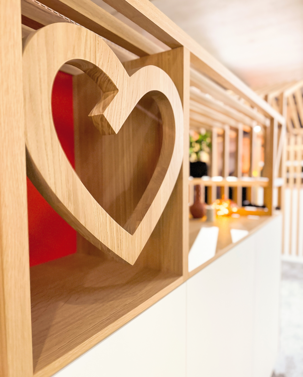 Wooden shelf with a heart-shaped cutout, part of a built-in cabinet.