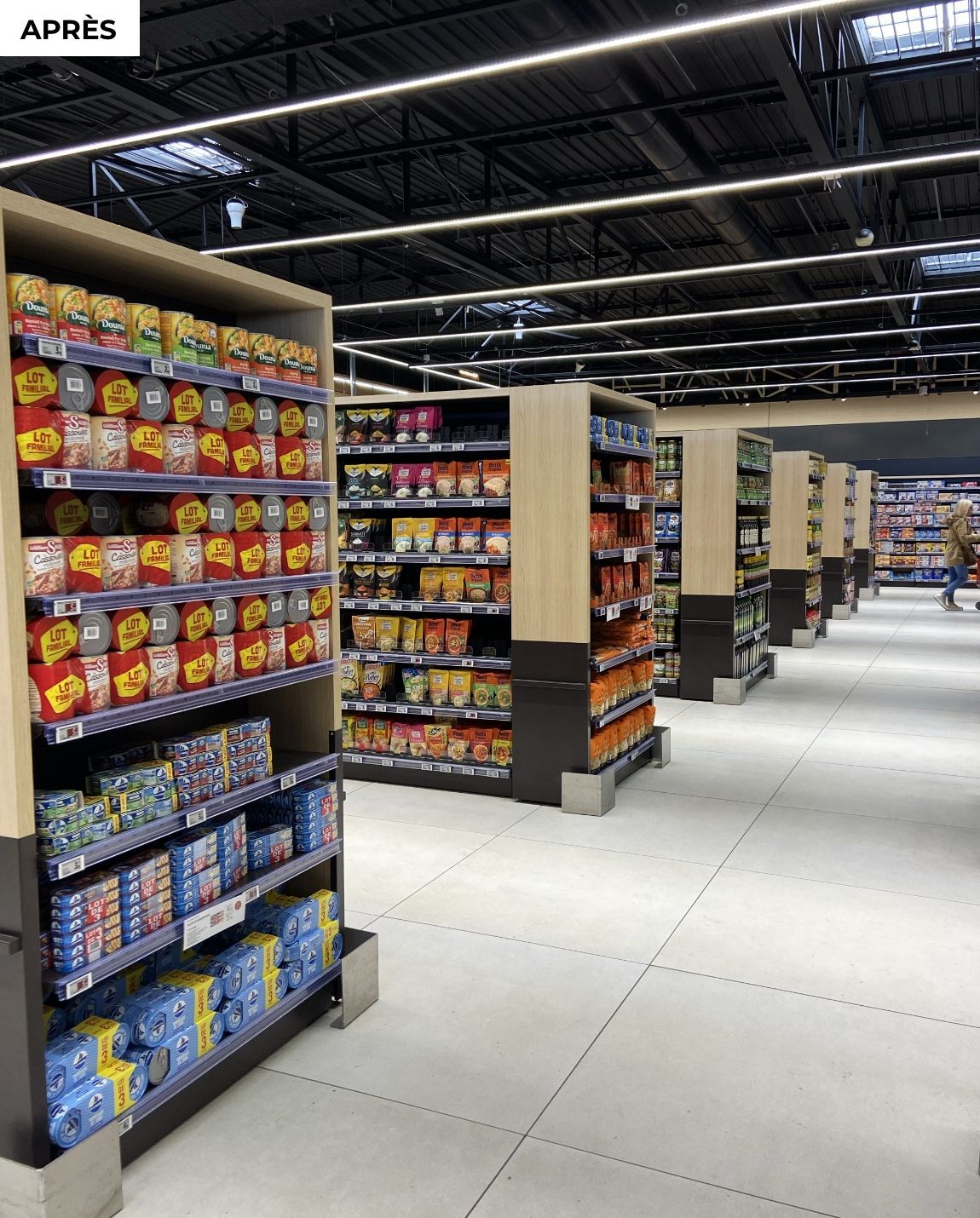 APRES  allée Hypermarché avec des étagères remplies de produits emballés colorés et un sol lumineux et ouvert.