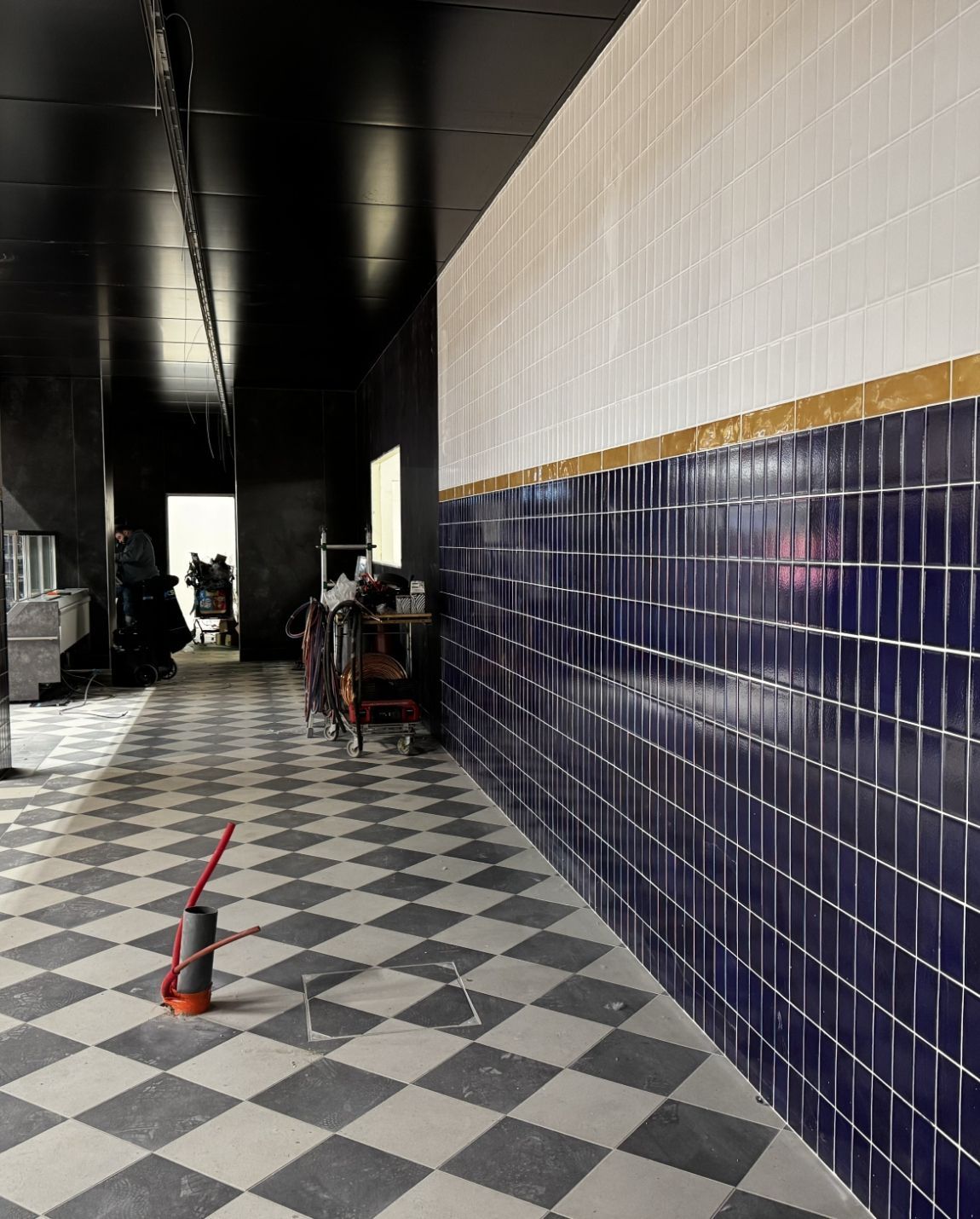 Intérieur d'une chocolaterie aux touches orange. Mur noir avec inscription en français et comptoir de caisse.