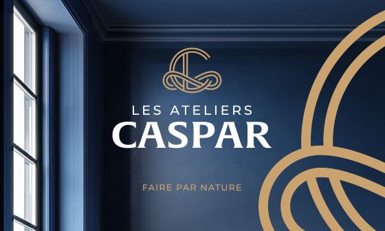 Les Ateliers Caspar logo on a navy blue wall. Gold logo and text. 