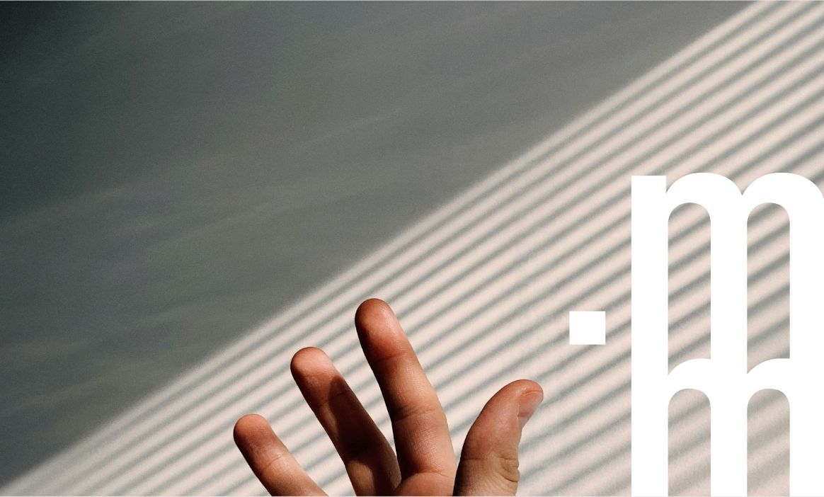 Hand reaching upward with striped shadows on a gray wall; white